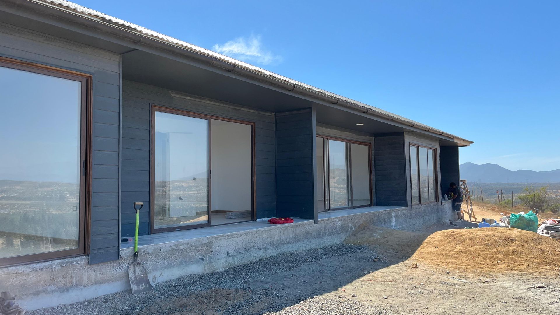 Casa de revestimiento oscuro con ventanales, obra real de Casas Quinta Región